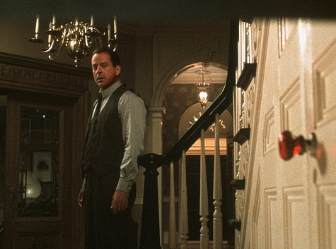A scene from the Sixth Sense, with Bruce Willis looking at a red door handle in the foreground